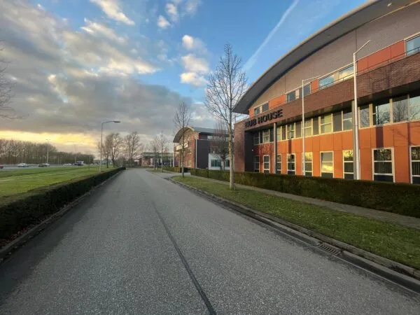 Kantoorgebouw genaamd "HUB HOUSE" aan een rustige straat bij zonsondergang.